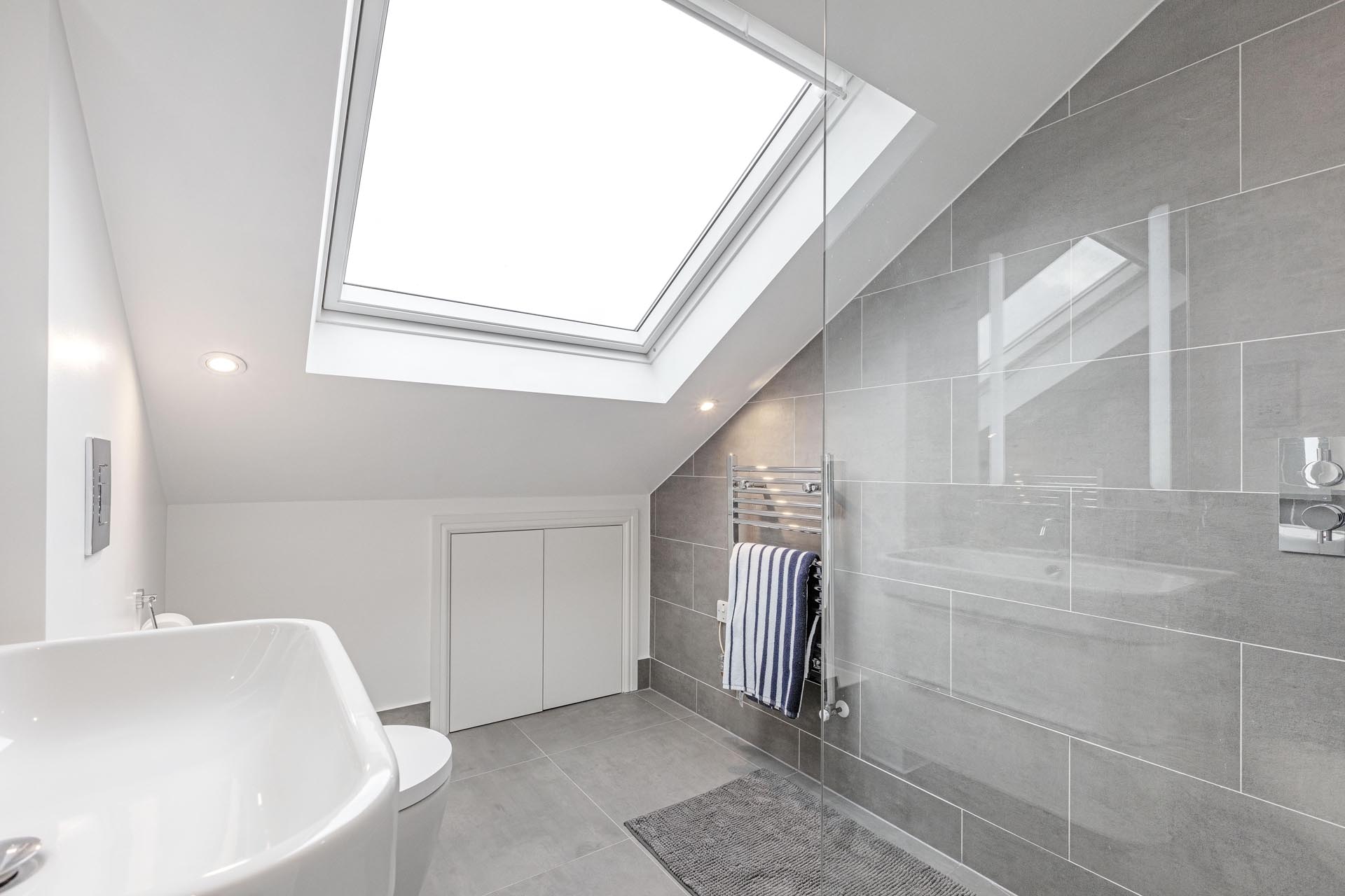 bathroom in the loft with white wall and grey tails on wall after conversion by loft conversion specialist london